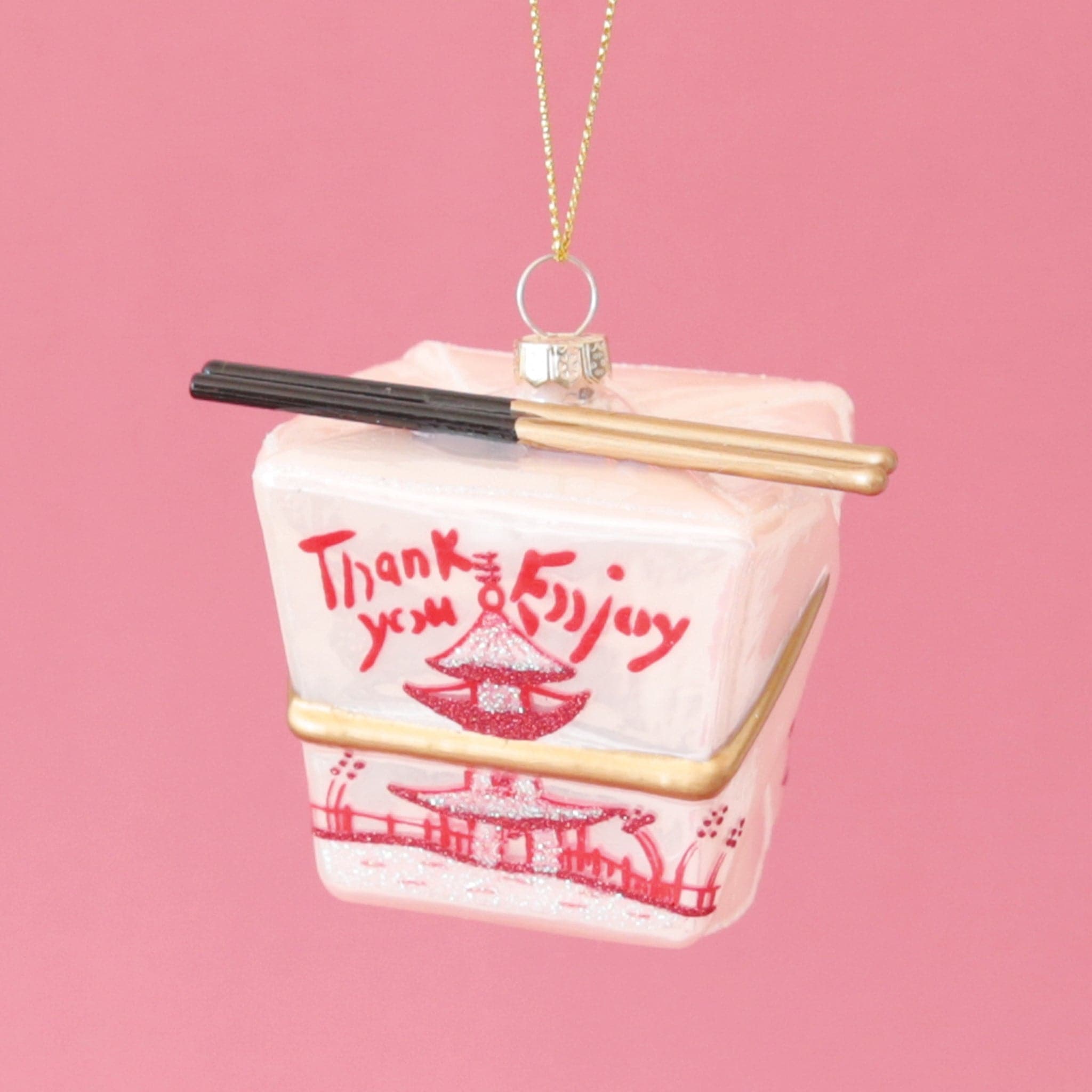 A glass ornament made to look like a pink Chinese takeout box with a pair of chopsticks across the top.