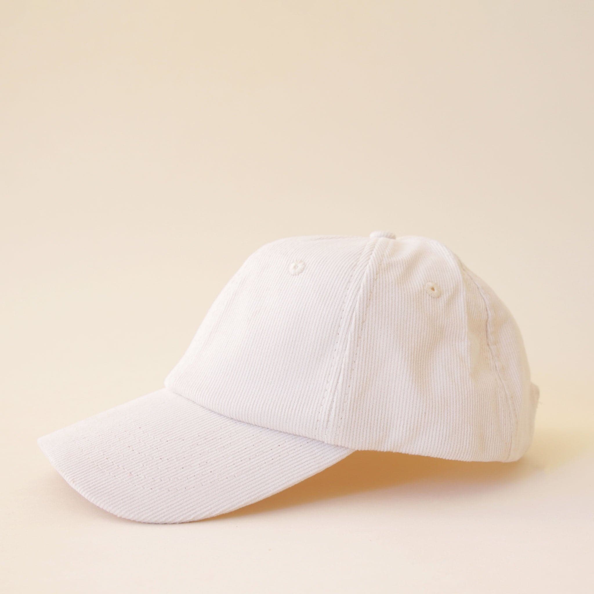An ivory corduroy baseball hat with a curved bill.