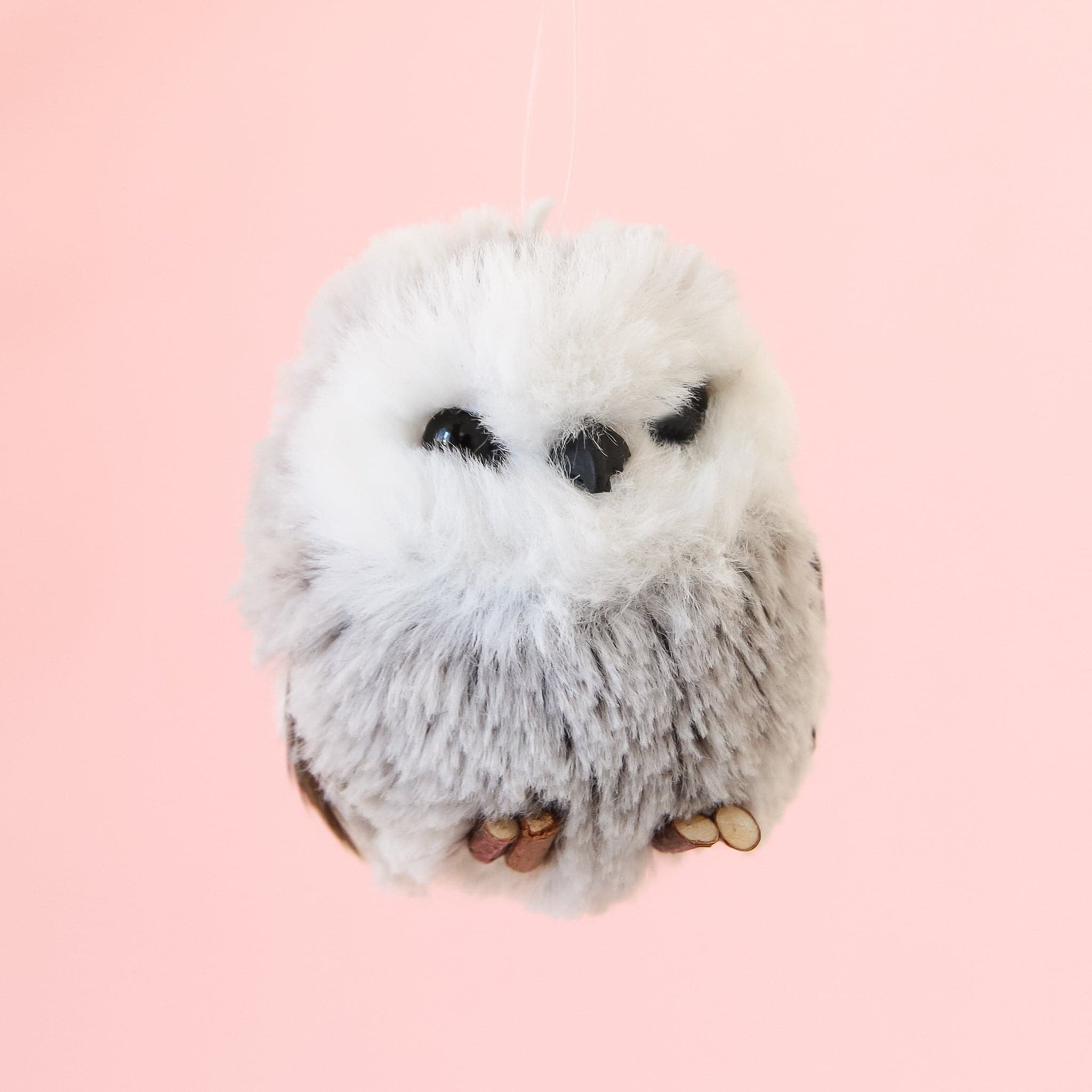 A gray and white owl ornament with a black beak and black eyes and a furry body.
