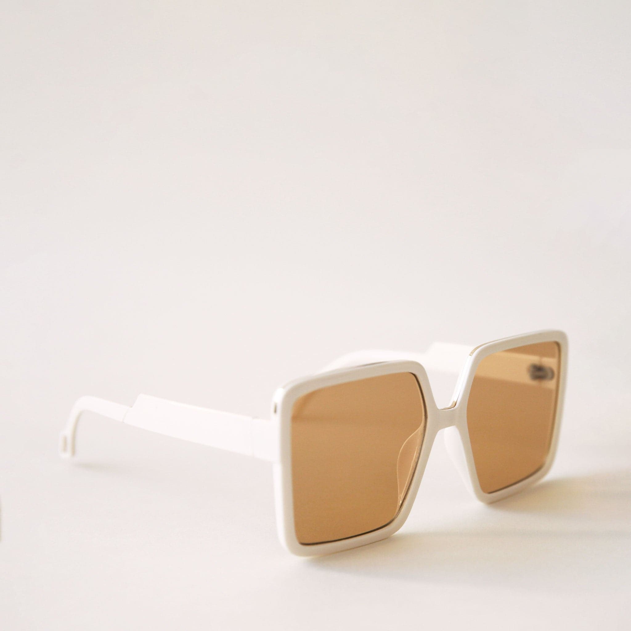 70&#39;s inspired square sunglasses with an oversized white frame and amber colored lenses.