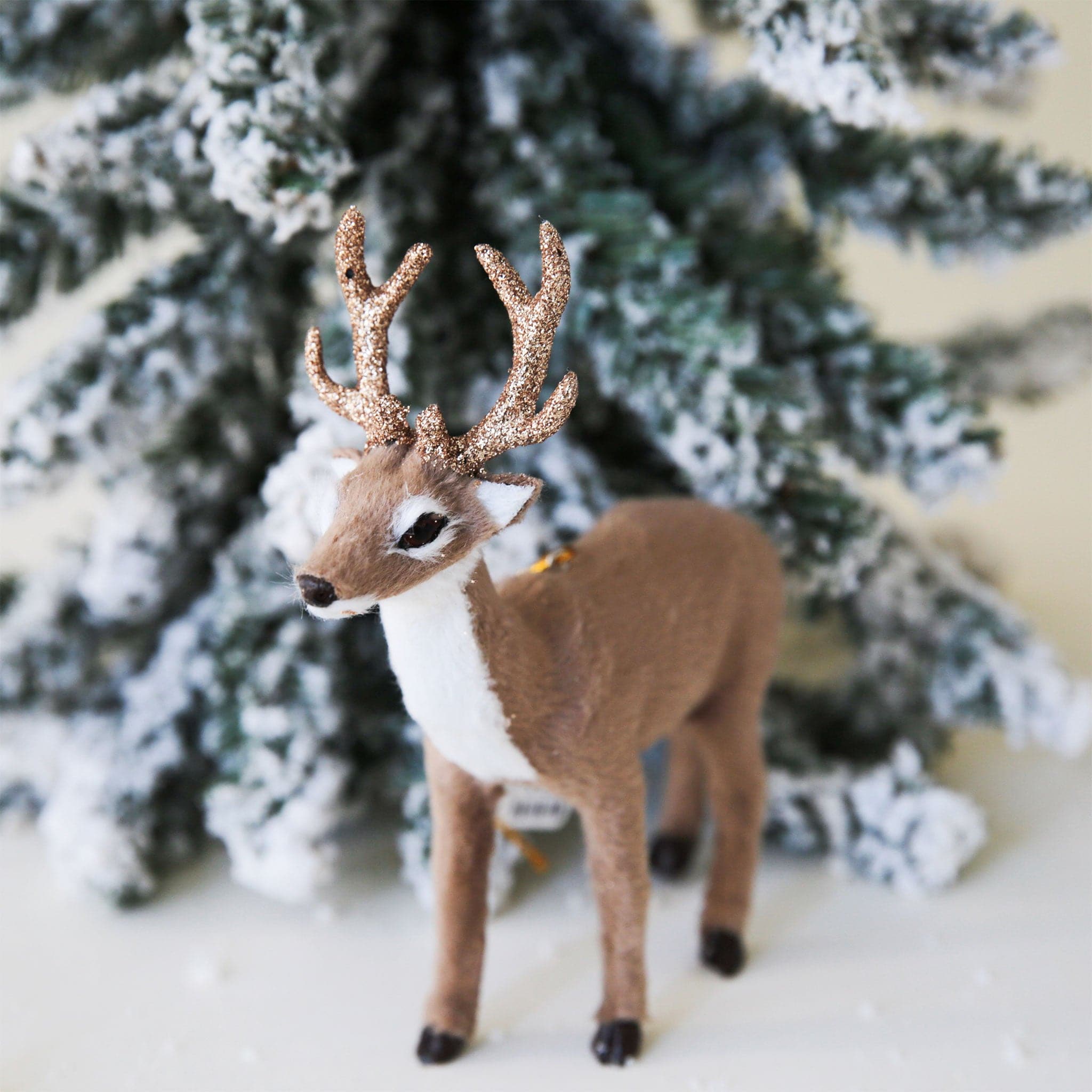 A furry white and brown stag holiday decor with glitter antlers.