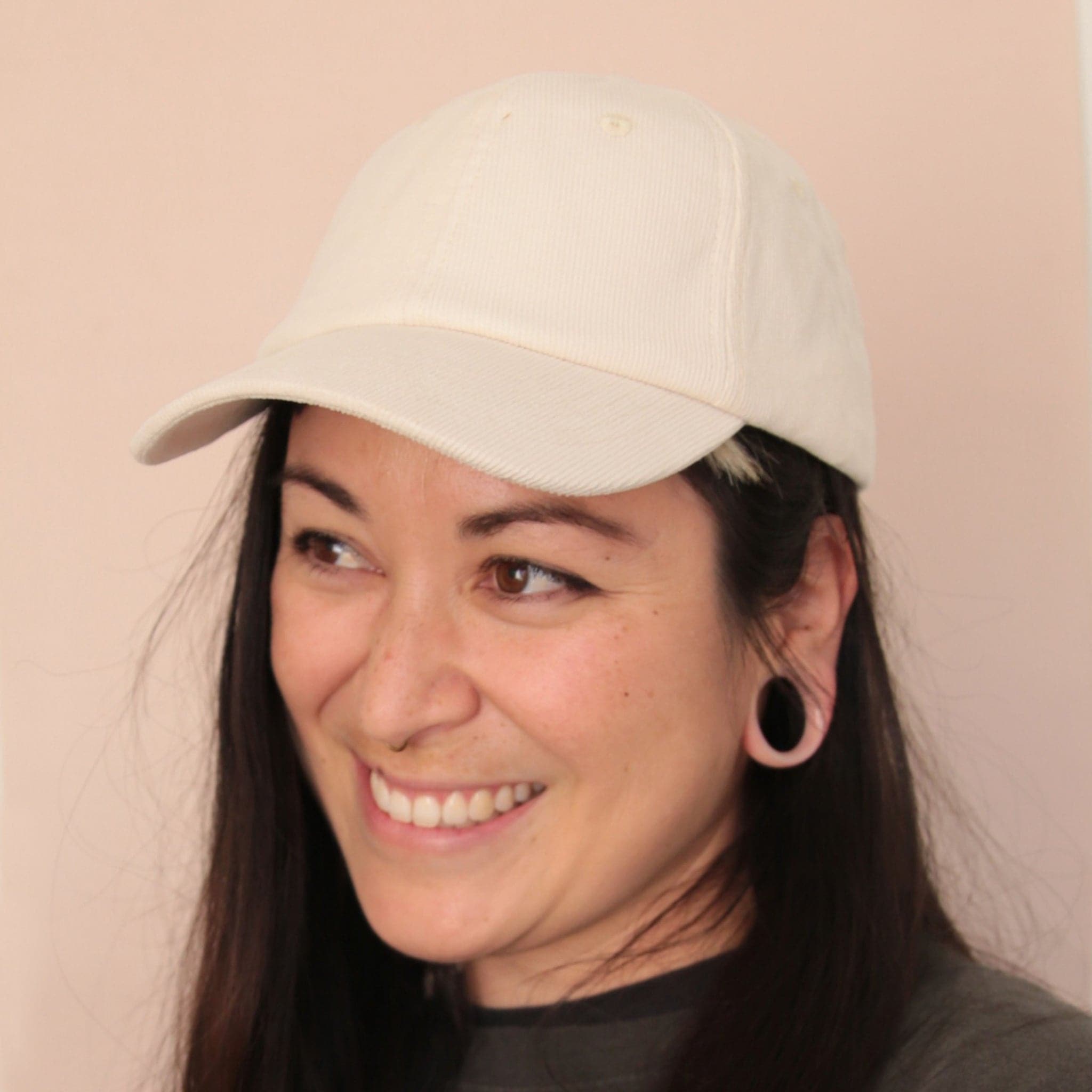 An ivory corduroy baseball hat with a curved bill photographed being worn on a model.