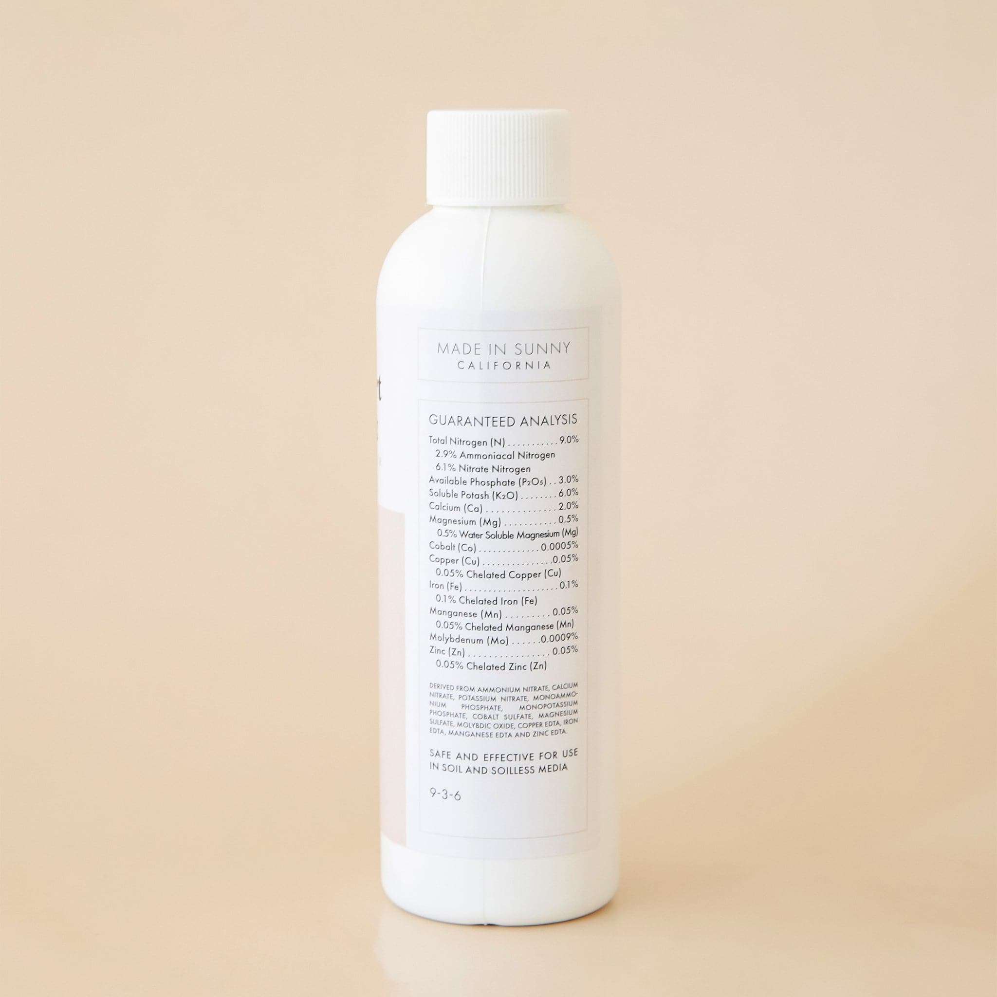 The back side of the bottle reads 'Made in Sunny California' in black capital lettering. Below is a detailed list of ingredients titled 'Guaranteed Analysis'. Both the title and ingredient lists are outlined in a thin, soft beige border. 