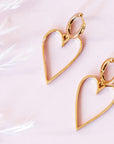 A pair of gold hoop earrings with a larger hold heart shape hoop attached to that.