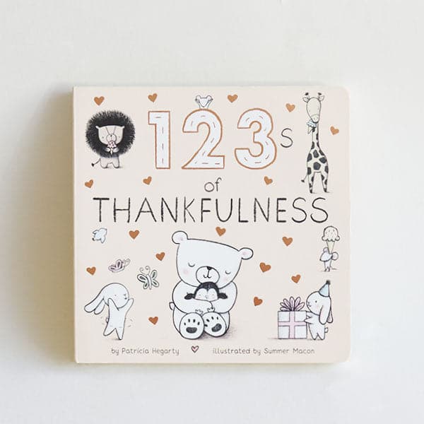 Small cream colored children's book titled "123's of Thankfulness" By Patricia Hegarty, Illustrated by Summer Macon. On the cover are illustrated gold hearts and black and white animals, including a lion, giraffe eating ice cream, mice, rabbits, and a bear hugging a baby penguin. 