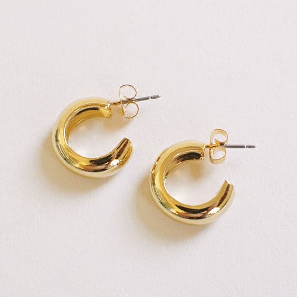 Chunky gold huggie hoop earrings with a straight post backing.