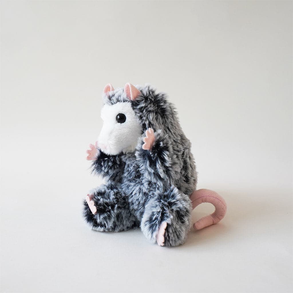 Excessively cute stuffed baby possum covered in ashy fur with frosted tips and pale pink paws, ears, nose and tail. The possum has a solid white face and a pair of black, gleamy eyes.