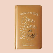 High quality, honey toned memory book reading 'Newlywed's one line a day; a three year memory book' in silver foil lettering across the padded cover. 