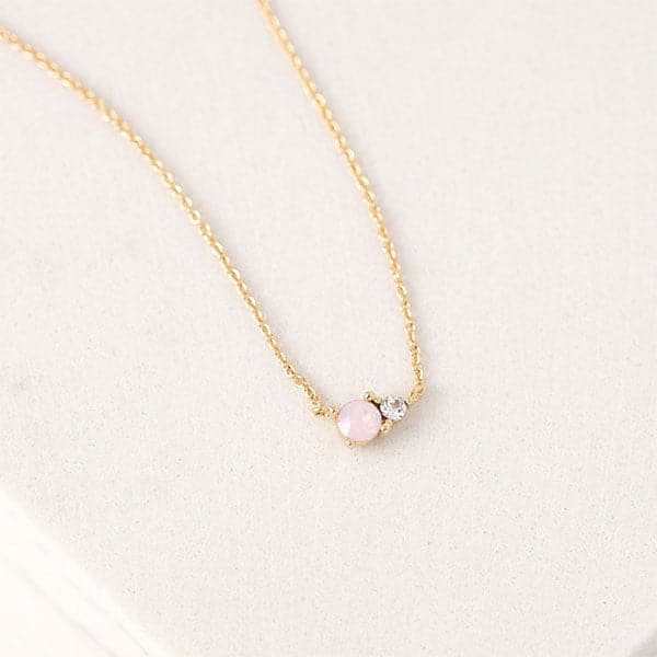 A dainty chain necklace with a circle pink opal accented with a smaller CZ diamond set right beside it.