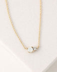 A dainty chain necklace with a circle white opal accented with a smaller CZ diamond set right beside it.