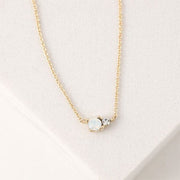 A dainty chain necklace with a circle white opal accented with a smaller CZ diamond set right beside it.