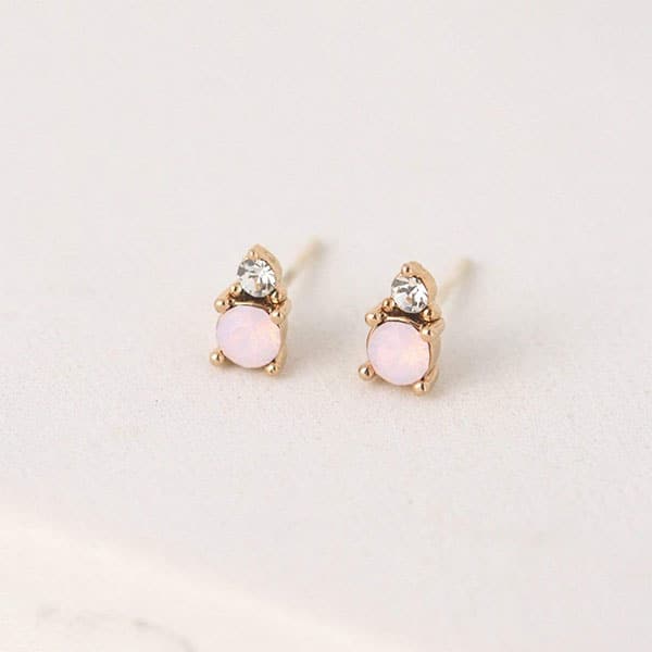 A pair of stud earrings featuring a dainty circular pink opal and a smaller Swarovski Crystal accent right above it.