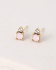 A pair of stud earrings featuring a dainty circular pink opal and a smaller Swarovski Crystal accent right above it.