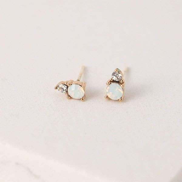 A pair of stud earrings featuring a dainty circular white opal and a smaller Swarovski Crystal accent right above it.