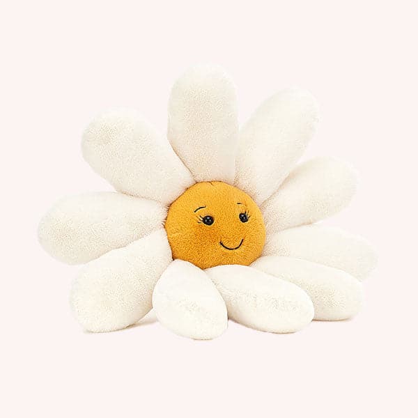 On a cream background is a white and yellow daisy stuffed animal with a smiling face in the center. 