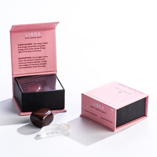 A pink magnetic box featuring the Libra&#39;s mini stone pack. It features and clear quartz crystal and a tumbled bloodstone.