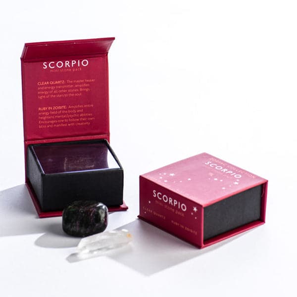 A maroon magnetic box featuring the Scorpio&#39;s mini stone pack. It includes a clear quartz crystal and a tumbled ruby in zoisite.