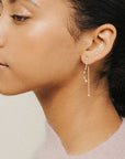 A dainty dangly earring with a star stud and a chain hanging down the back side and a wavy cubic zirconia studded down the front.