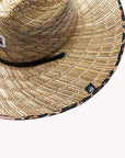 Against a white background is the top view of a wide brim, straw hat. The brim has a black and brown cheetah print border. On the front of the hat is a cheetah print diamond with three white trees inside. The black drawstring goes around half of the top of the hat.
