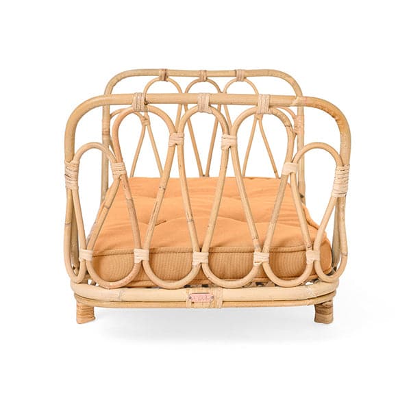 In front of a white background is the side view of a light tan wicker day bed. The sides have a thick border with thin wicker wave design. Inside the day bed is an orange mattress. 