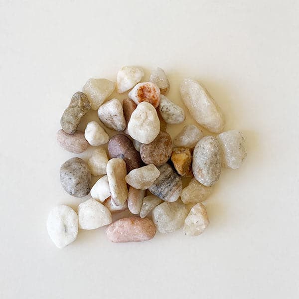 On a cream background is an assortment of natural tan and cream colored stones. 