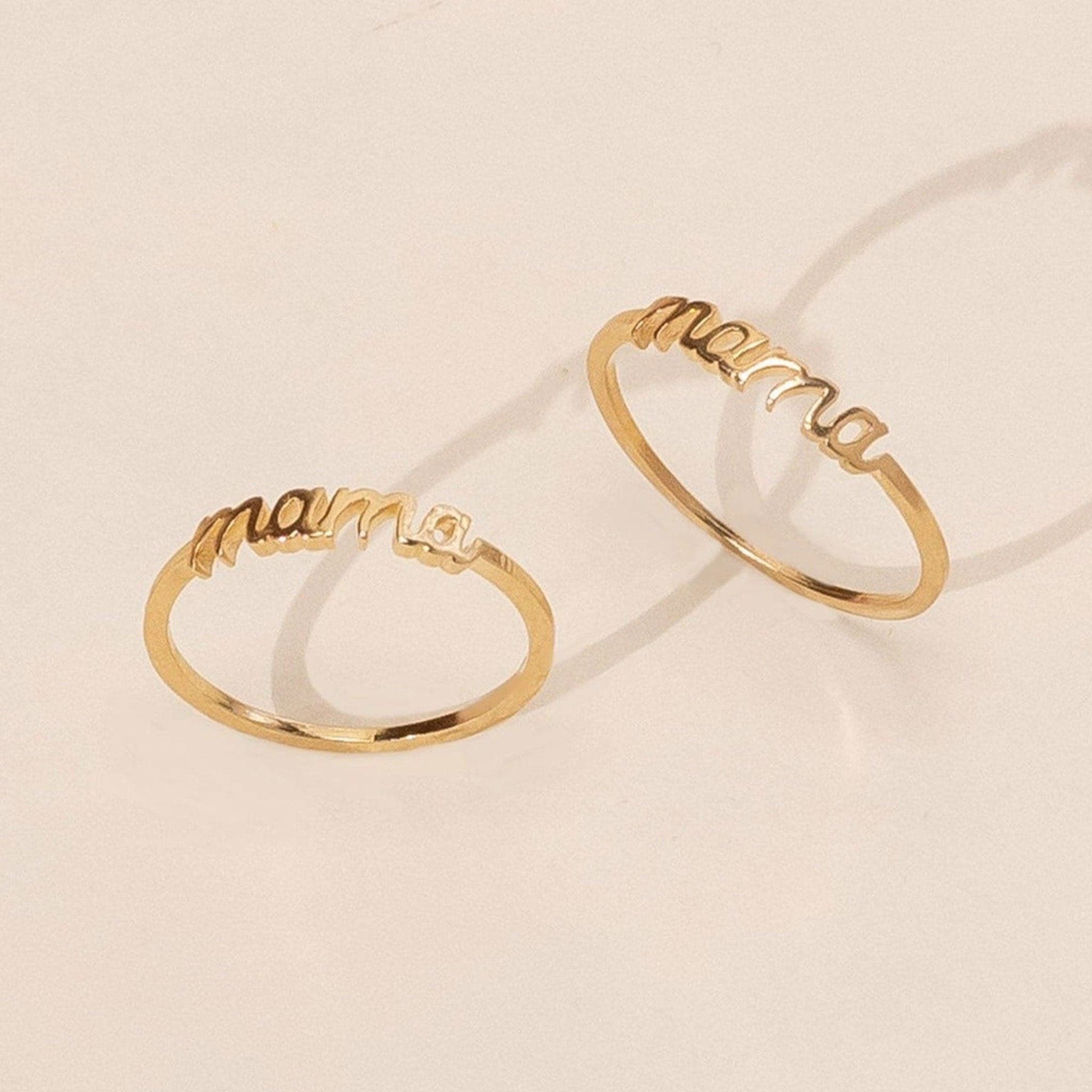 Two gold rings that reads 'mama' in cursive within the band. Each ring sold sparely. 