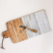 On a cream background is a wood and grey marble cutting board with a coordinating butter knife. 