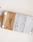 On a cream background is a wood and grey marble cutting board with a coordinating butter knife.