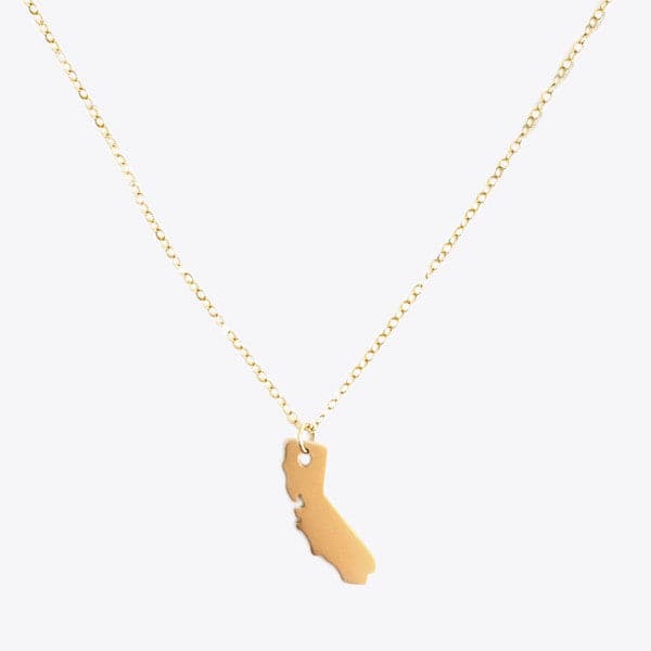 A dainty gold chain necklace with a small gold pendant that is in the shape of the state of California. 