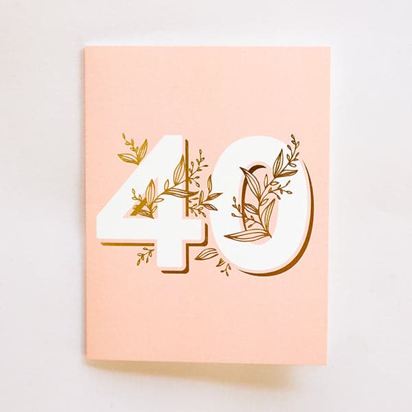 A light blush pink card with the numbers &quot;40&quot; in the center with gold foiled vining wrapped around and throughout it along with a white envelope.