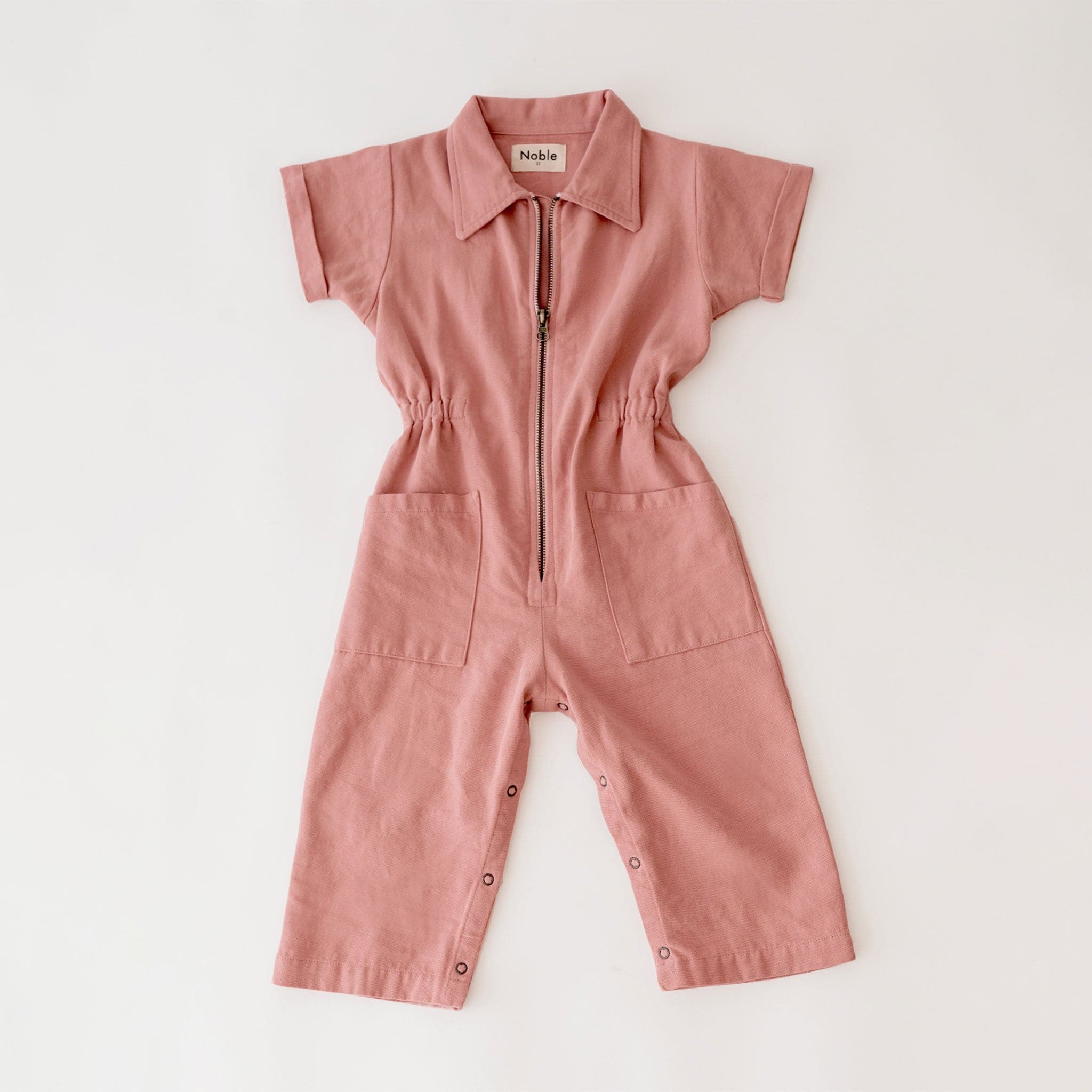 A short sleeved utility jumpsuit in the sweetest dusty rose shade. There is a front zipper and a two pockets.