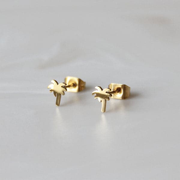 In front of a white background is a pair of gold palm tree studs. 