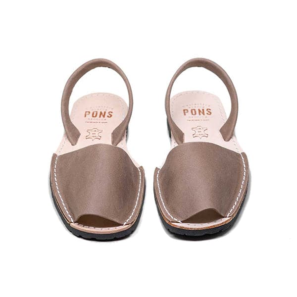 Single Avarca sandal made of dark rubber molded to a light natural leather sole. The sandal's front strap is a taupe leather and large enough to cover the front half of foot. On the back half is a thin leather ankle strap that wraps on the back side. 'Pons' is written on the sole in burnt orange lettering. 