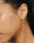 A dainty dangly earring with a star stud and a chain hanging down the back side and a wavy cubic zirconia studded down the front.