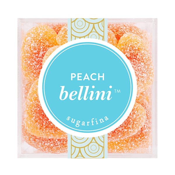 Birds eye view of the top of a clear plastic cube container. The container is filled with peach colored heart shaped gummies coated in white sugar. On the top of the container is a bright blue circle sticker with white text that reads ‘peach Bellini.’