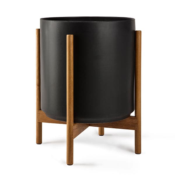 This cylinder pot is solid black and sits within four spokes of a neutral wood plant stand, standing about 5.5 inches from the ground. 