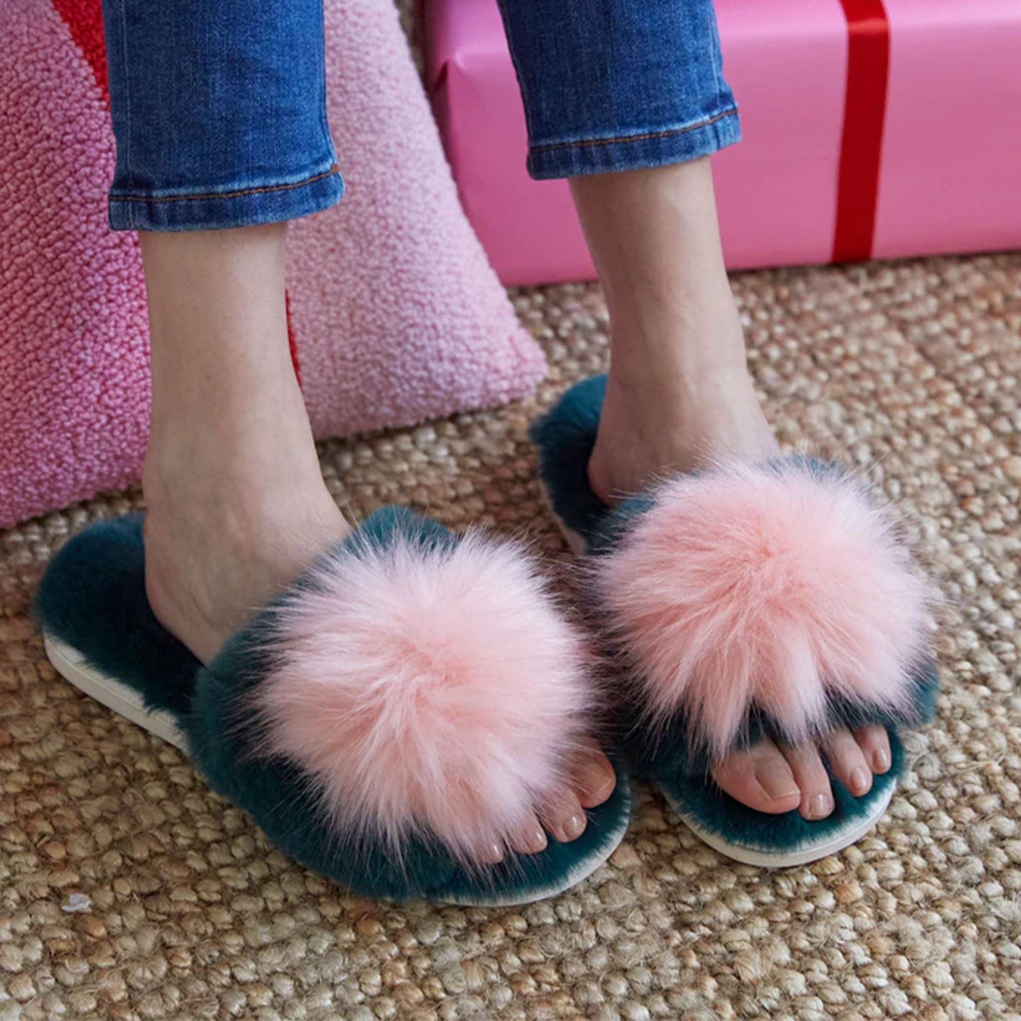 Green fuzzy slide on slippers with a pink fuzzy pom on the center of each one.