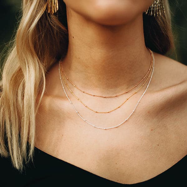 Woman modeling Aria Necklace, find gold chain with small beads.