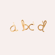 Four gold stud earrings of bent wire in the shape of the lowercase letters A, B, C and D.