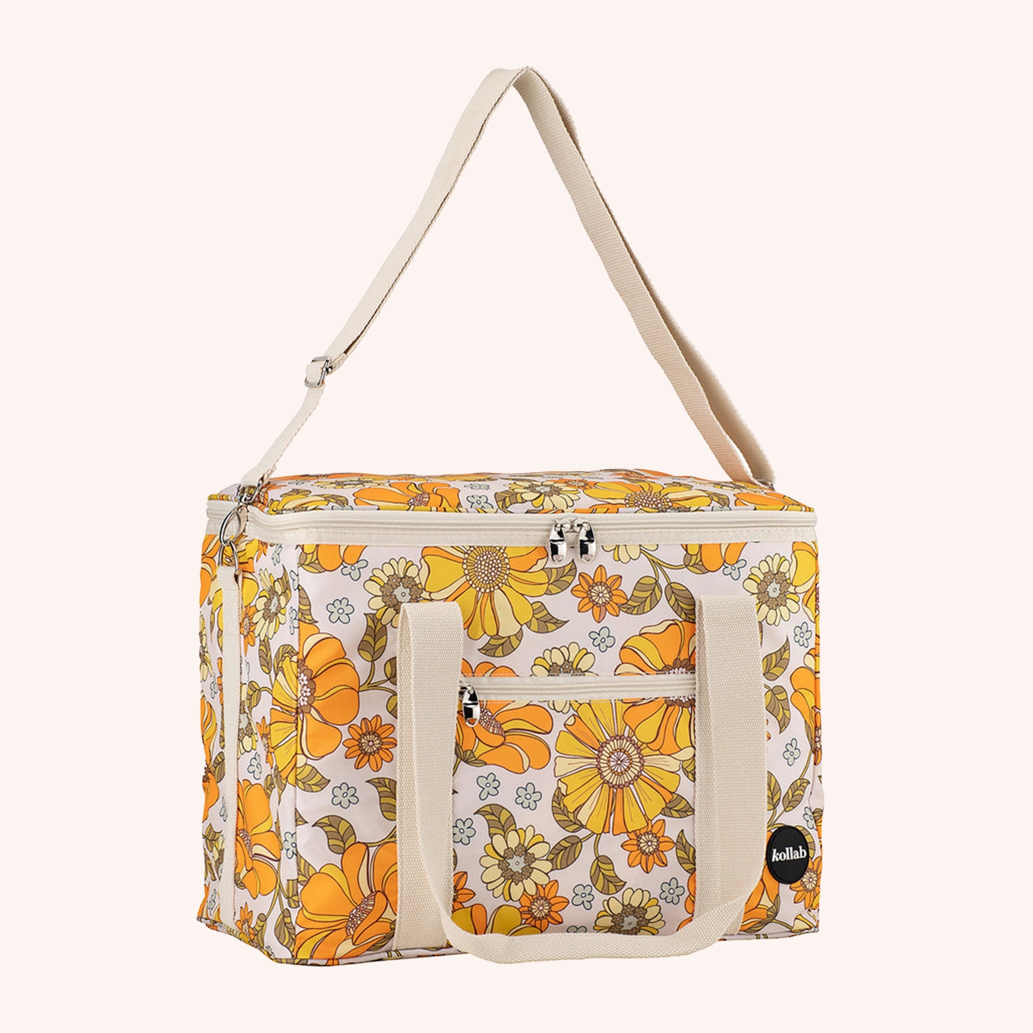 Photographed in front of a yellow background is a picnic bag with cream straps and 70's style yellow and orange floral print.