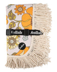 A 70's style yellow and orange floral picnic mat with cream fringe detailing around the edges.