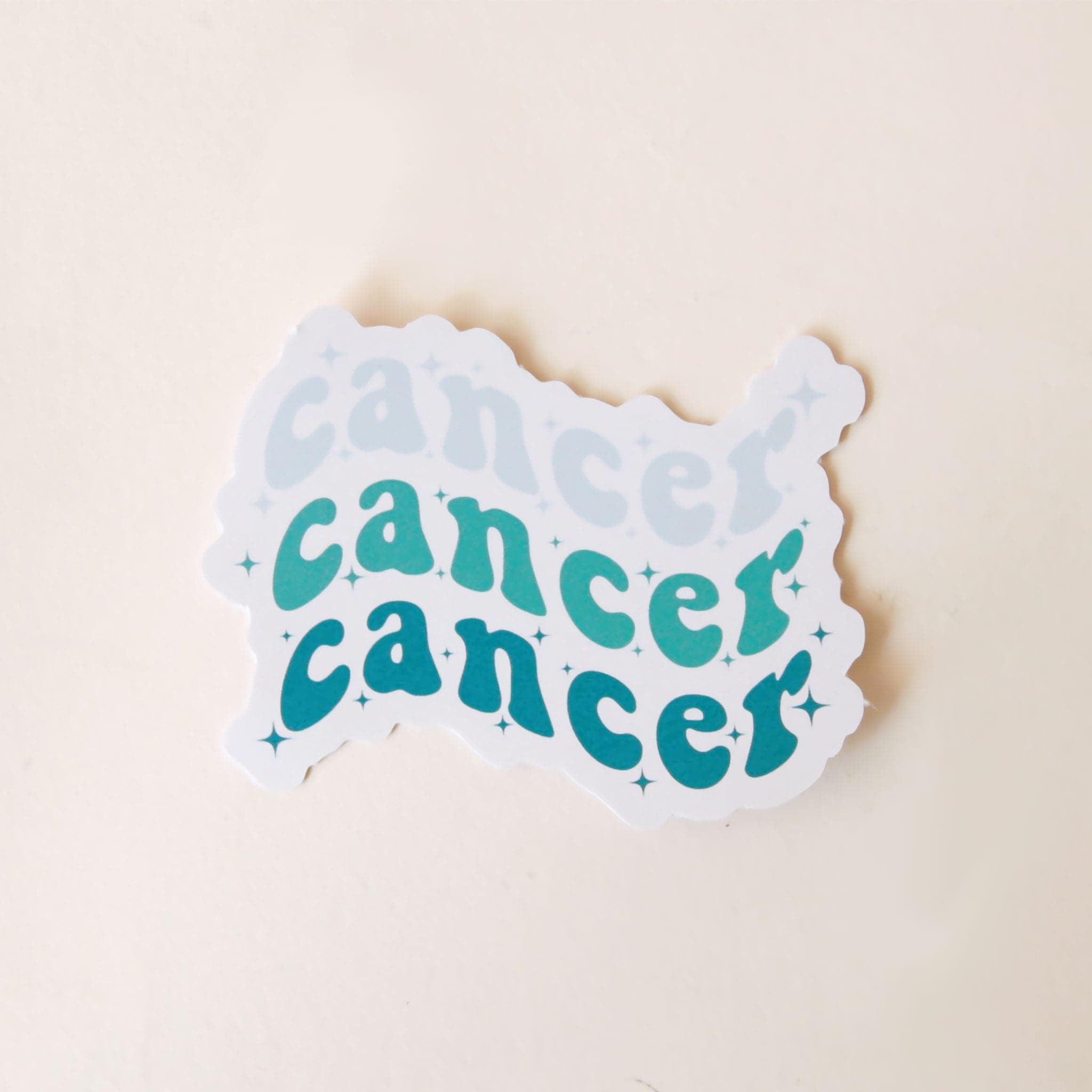 On a white background is a blue sticker with the word &quot;Cancer&quot; stacked on top of one another three times. 