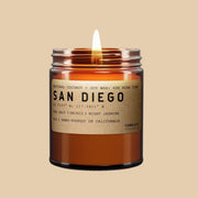 A glass amber jar with a natural colored label that reads, "San Diego" along with the details of the candle. This candle's scent is made of sea salt, orchid and night jasmine.
