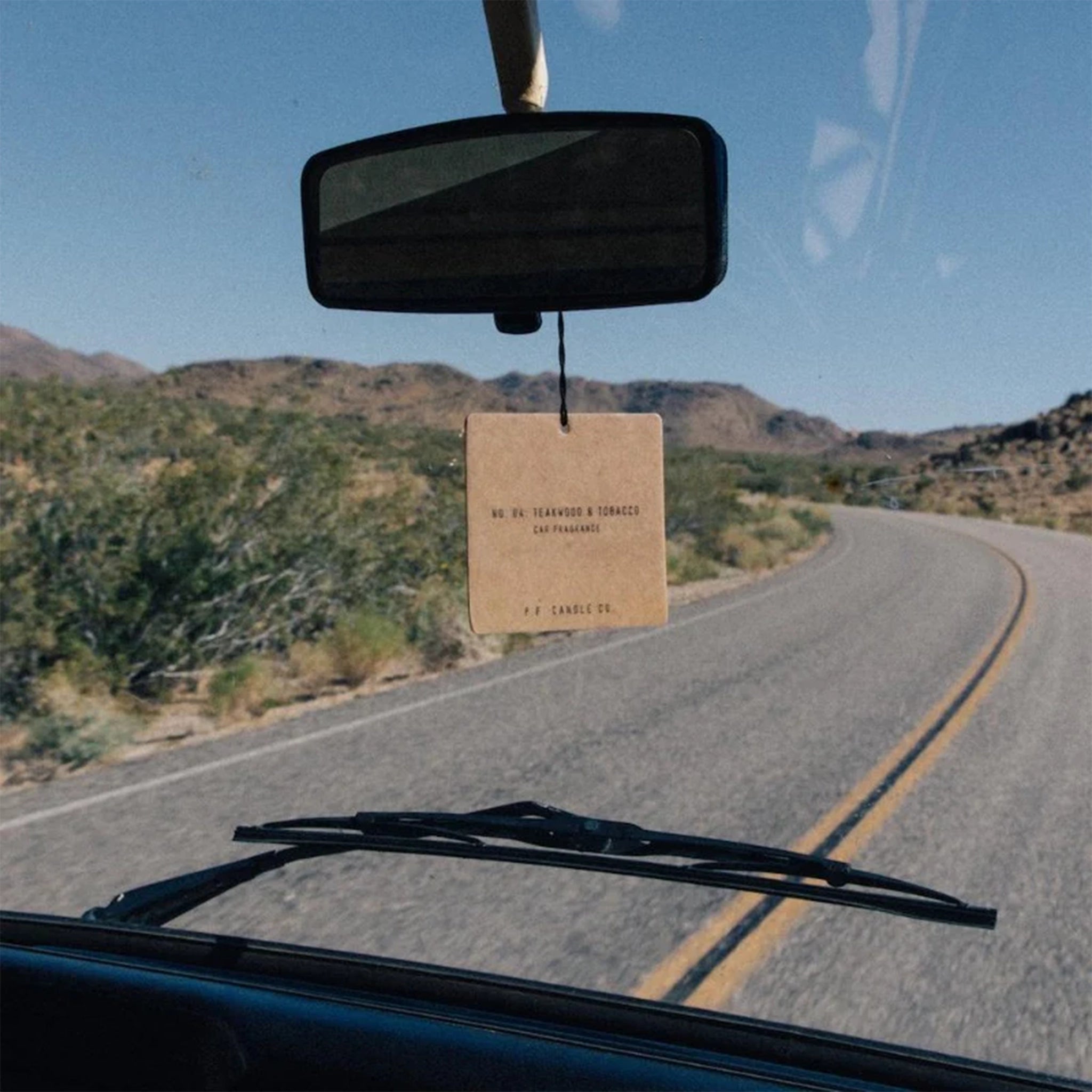 The square cardboard car fragrance hanging from the rear view mirror of a car.