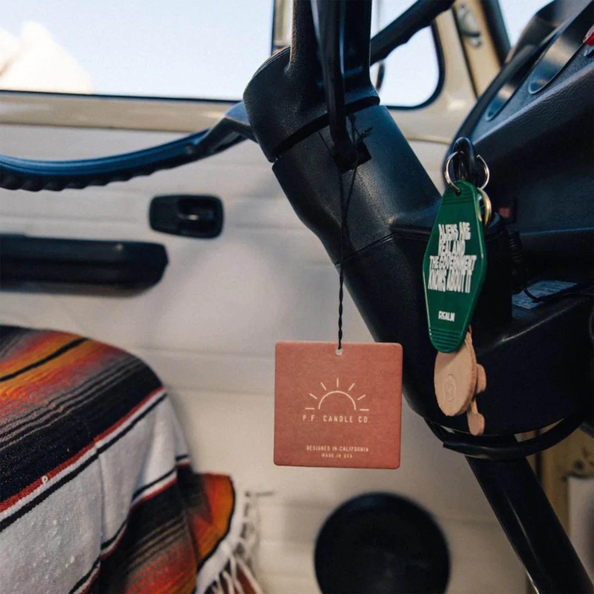 The square cardboard car fragrance hanging on the rear view mirror of a car.