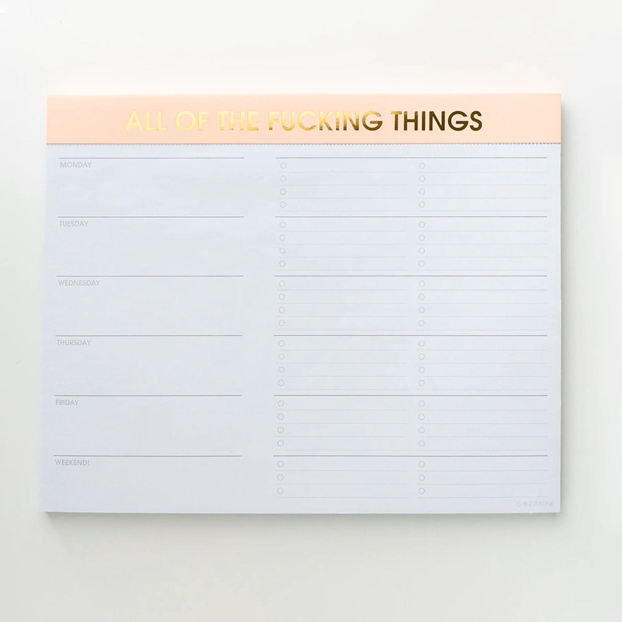 Weekly note pad with one column listing the days of the week, and next to each day are bullet pointed spaces to fill in your needs. The binding at the top is light yellow with gold foil letters saying, "All of the fucking things."