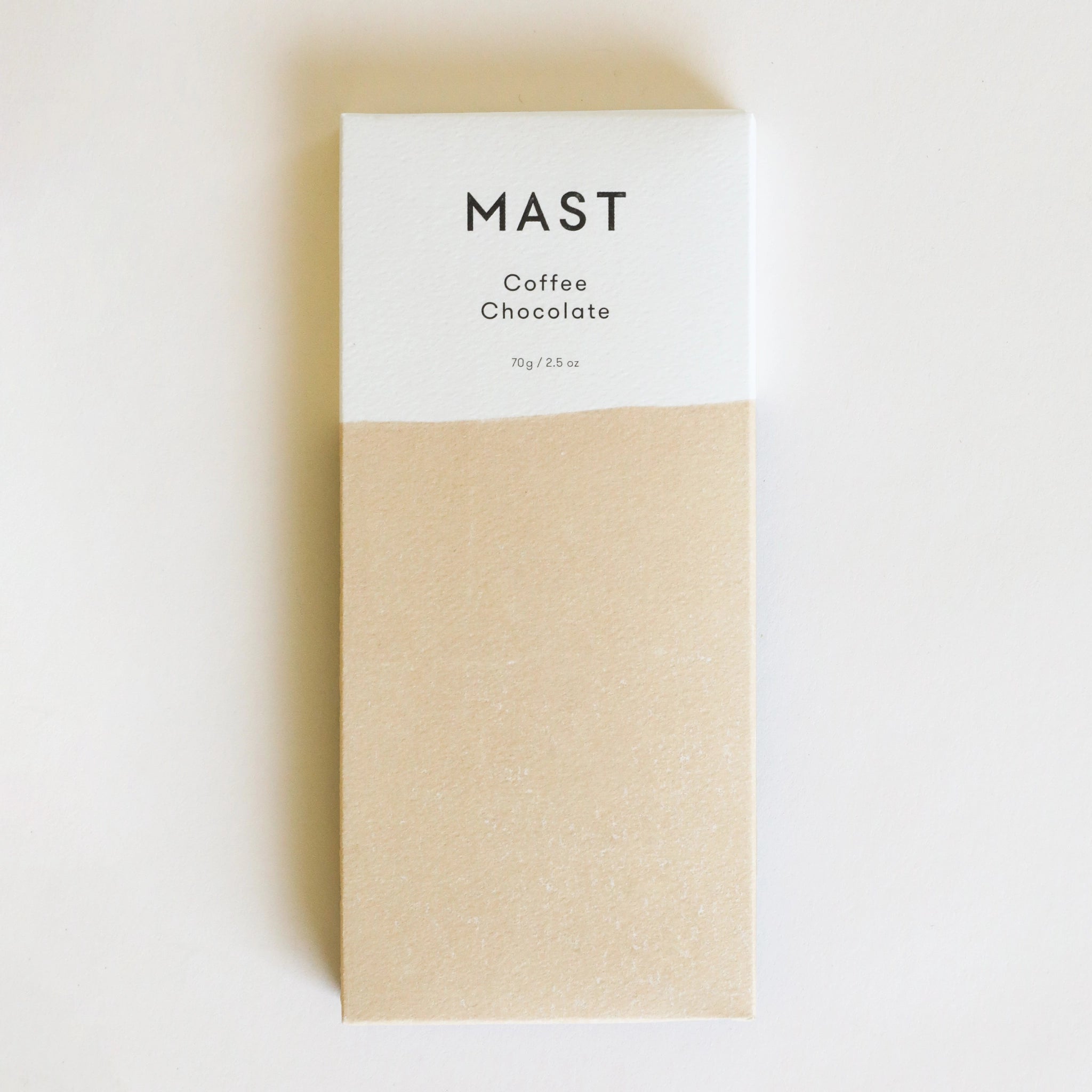 A rectangle chocolate bar packaged in a white and tan wrapper with black text that reads, &quot;MAST Coffee Chocolate&quot;.