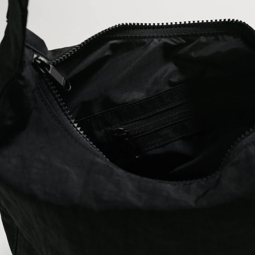 A nylon crescent shoulder bag with an adjustable strap and a single zipper. The interior also features a zipper for optimal organization.