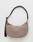 A taupe nylon crescent shaped bag with an adjustable black strap and a single zipper.