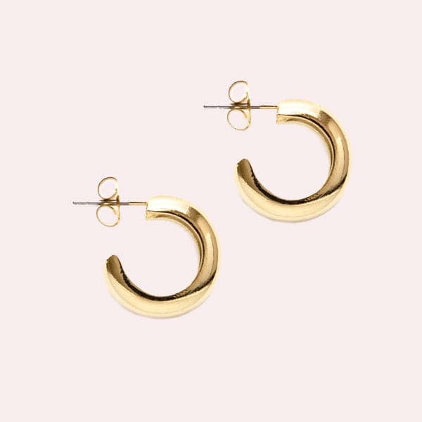 Chunky gold huggie hoop earrings with a straight post backing.